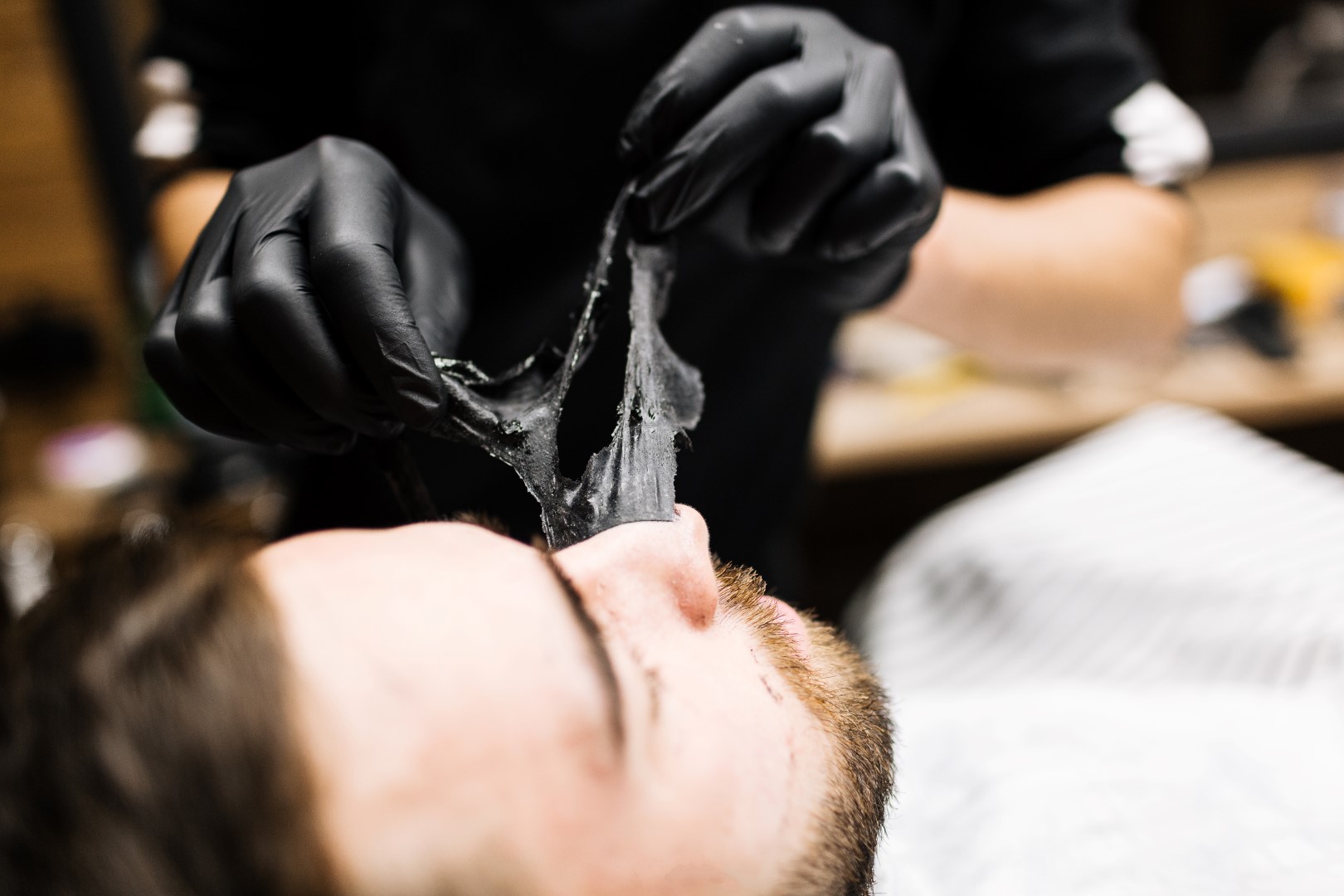 worker pulling off a beauty mask from a men's facial